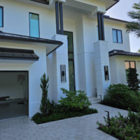 Exterior shot of a modern, Miami style, white home with the sun setting in the background.