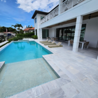 Modern home with crystal clear walk in pool. White stone coping and decking surround the pool.